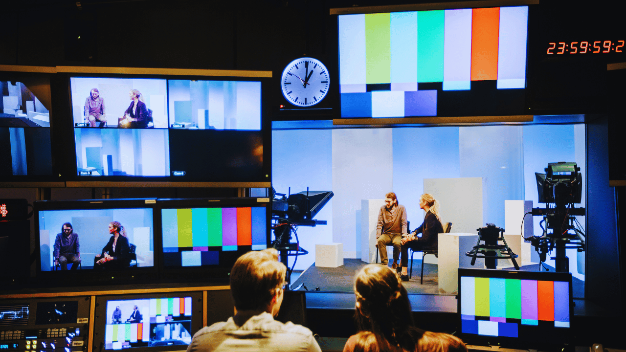 Image of a TV studio with multiple screens showing different views of a broadcast and color bars. The scene highlights the impact of the NTV cyber attack on the station's operations.