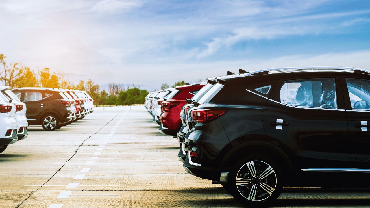 A row of parked vehicles at a dealership under a clear sky, illustrating the risks of purchasing re-vinned vehicles. Learn how to spot re-vinned vehicles and protect your business from fraudulent sales.