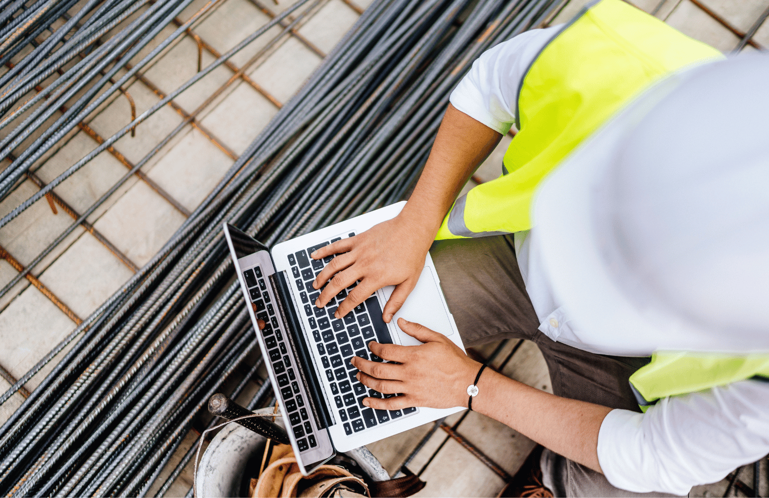 Construction worker in a safety vest using a laptop on-site, symbolizing the growing digital connectivity and cyber risks in the construction industry.