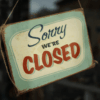 A vintage style sign hanging in a shop window that reads Sorry we’re closed, illustrating how unexpected closures can disrupt business operations.