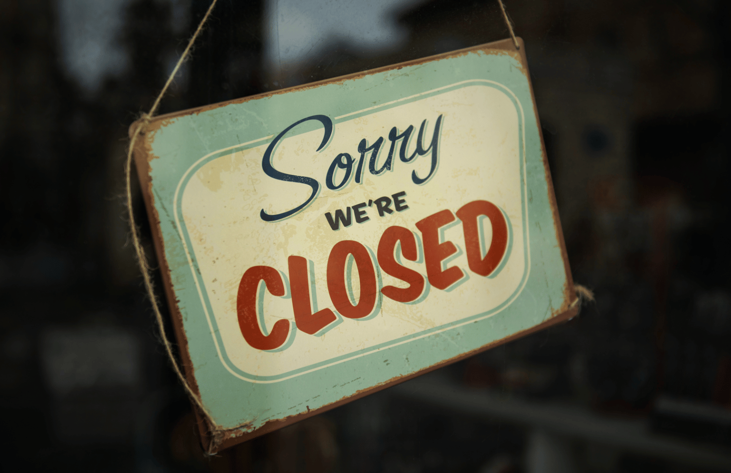 A vintage style sign hanging in a shop window that reads Sorry we’re closed, illustrating how unexpected closures can disrupt business operations.