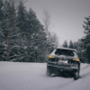 A car partially off a snowy road surrounded by wintery forest conditions, illustrating the hazards of winter driving in Newfoundland and the importance of preparing for storms and knowing what to do after an accident.
