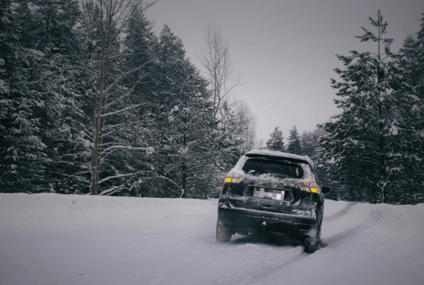 A car partially off a snowy road surrounded by wintery forest conditions, illustrating the hazards of winter driving in Newfoundland and the importance of preparing for storms and knowing what to do after an accident.