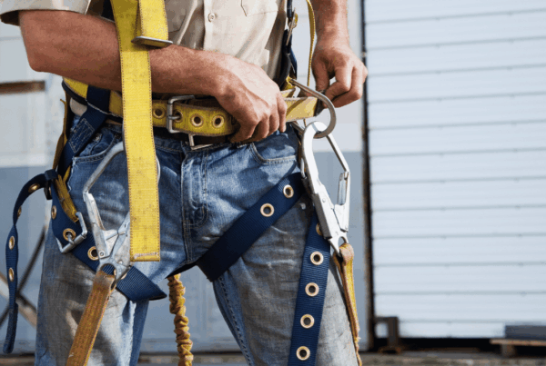 Worker securing a safety harness before starting work on a job site, highlighting the importance of personal protective equipment in a safety-first work culture.