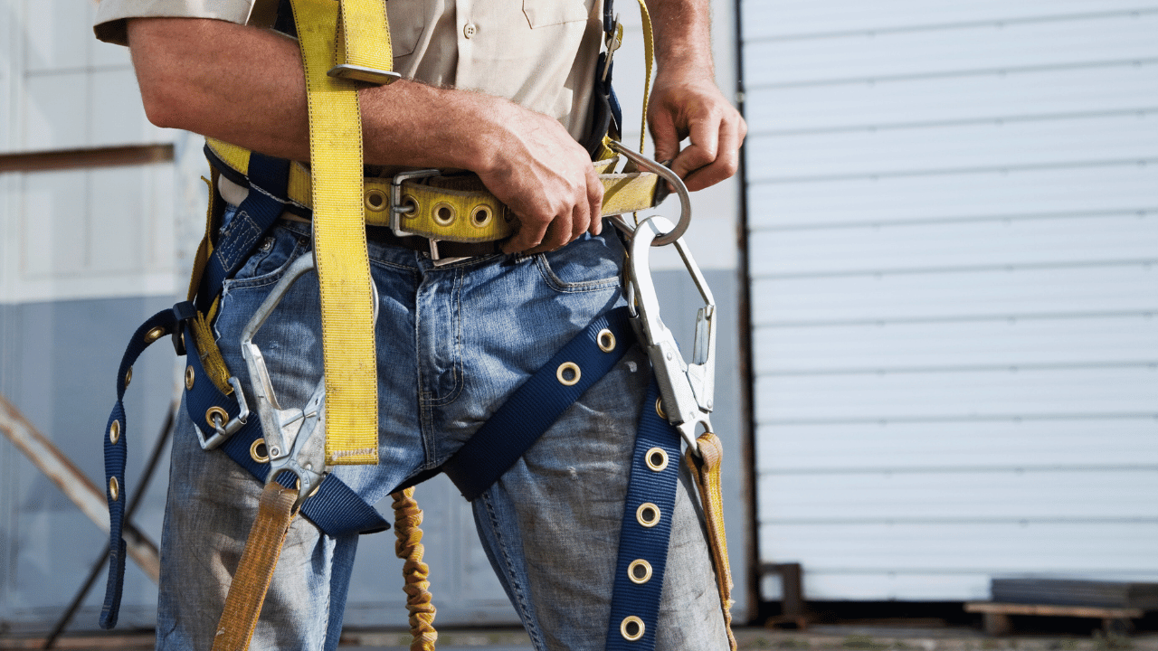 Worker securing a safety harness before starting work on a job site, highlighting the importance of personal protective equipment in a safety-first work culture.
