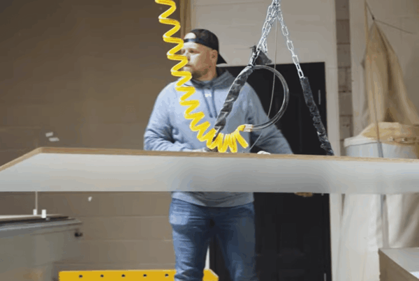 Dennis Park of Urban Woodworks, lifts a piece of MDF board with a suction grip.