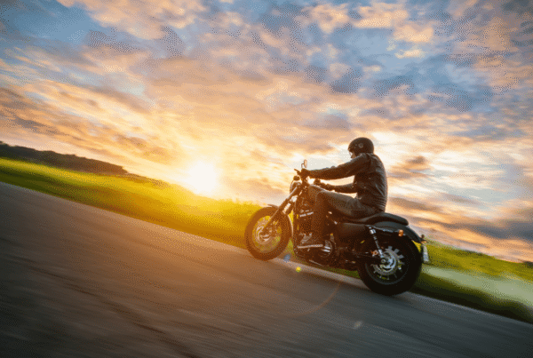Motorcycle rider on an open road at sunset, representing spring riding season in Newfoundland